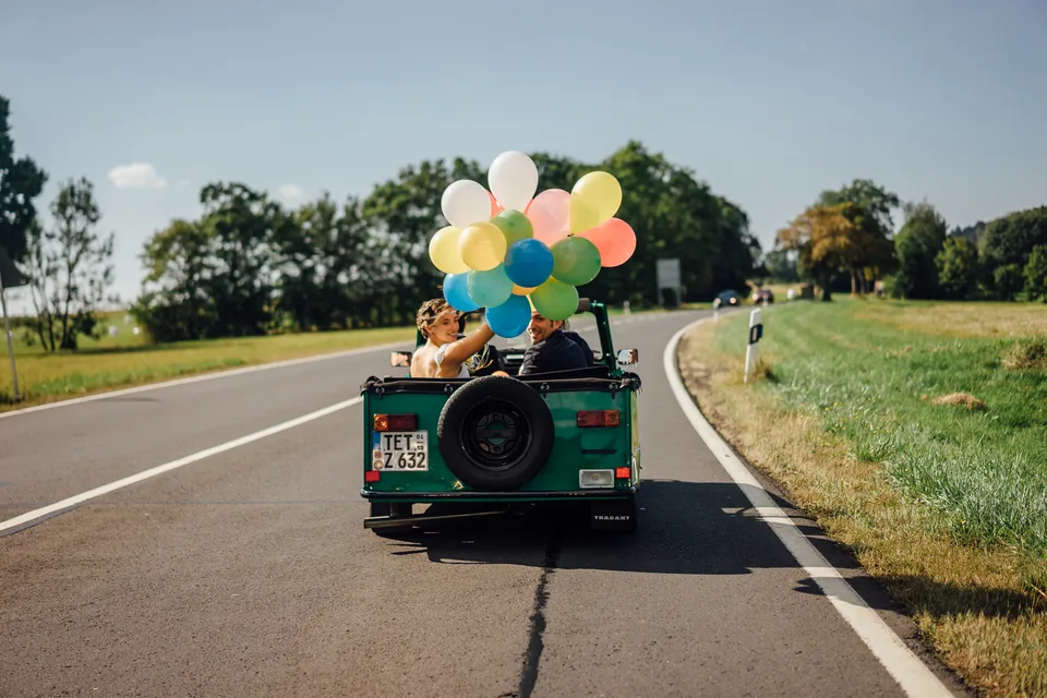 Hochzeitsauto mit Luftballons auf einer Landstraße